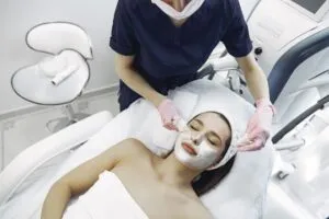 Profissional de estética com luvas realizando técnica de extração no rosto de uma cliente