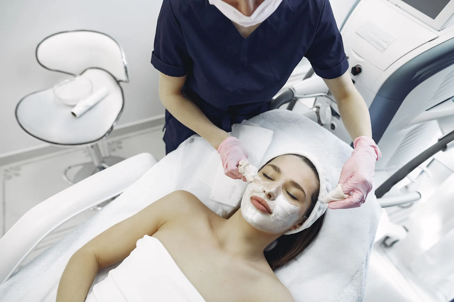 Profissional de estética com luvas realizando técnica de extração no rosto de uma cliente